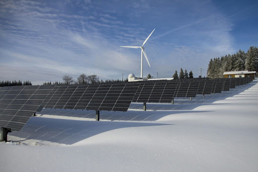 Renewable energy systems, wind turbines, and solar panels, in the snow